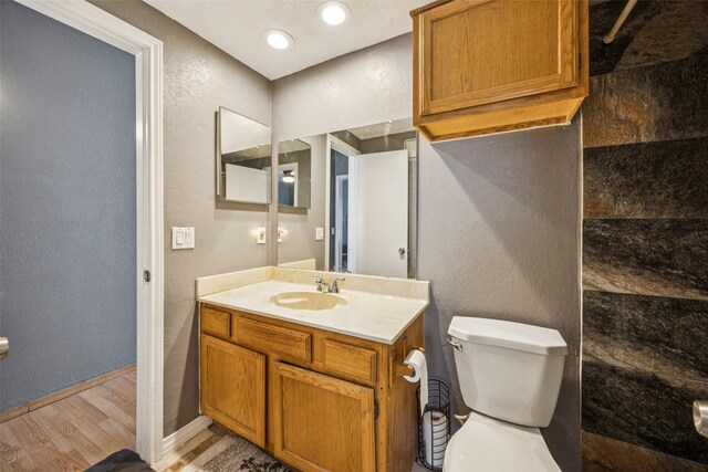 7340 Skillman St Unit 1207, Dallas, TX 75231 - bathroom featuring toilet, wood finished floors, a textured wall, vanity, and baseboards