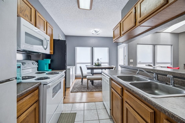 7340 Skillman St Unit 1207, Dallas, TX 75231 - kitchen with white appliances, a sink, brown cabinetry, light tile patterned floors, and a textured ceiling