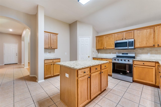 1117 Red Hawk Dr, Frisco, TX 75033 - kitchen with appliances with stainless steel finishes, arched walkways, light tile patterned floors, backsplash, and vaulted ceiling