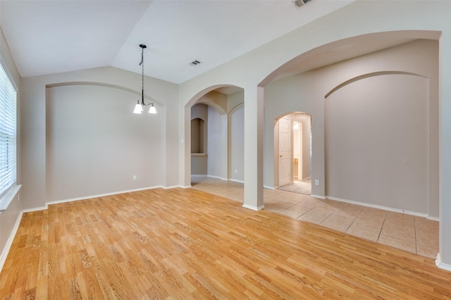 1117 Red Hawk Dr, Frisco, TX 75033 - empty room with light wood-type flooring, arched walkways, lofted ceiling, a chandelier, and baseboards