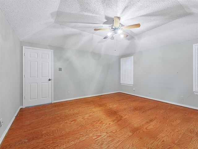 211 Indian Trace Ln, Waxahachie, TX 75165 - empty room featuring a textured ceiling, wood finished floors, ceiling fan, vaulted ceiling, and baseboards