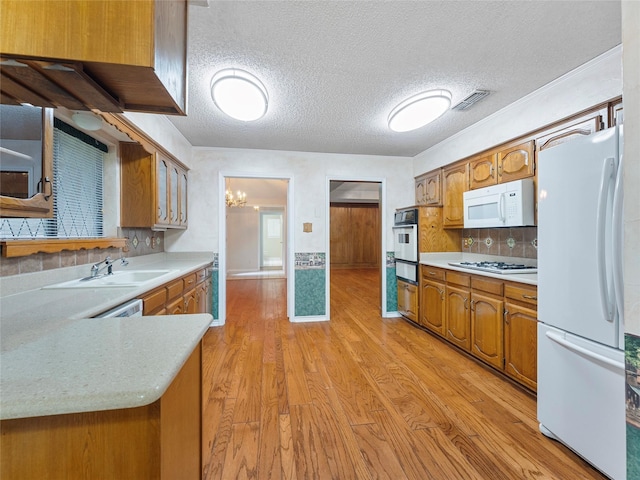 211 Indian Trace Ln, Waxahachie, TX 75165 - kitchen featuring white appliances, a sink, light countertops, brown cabinets, and a textured ceiling