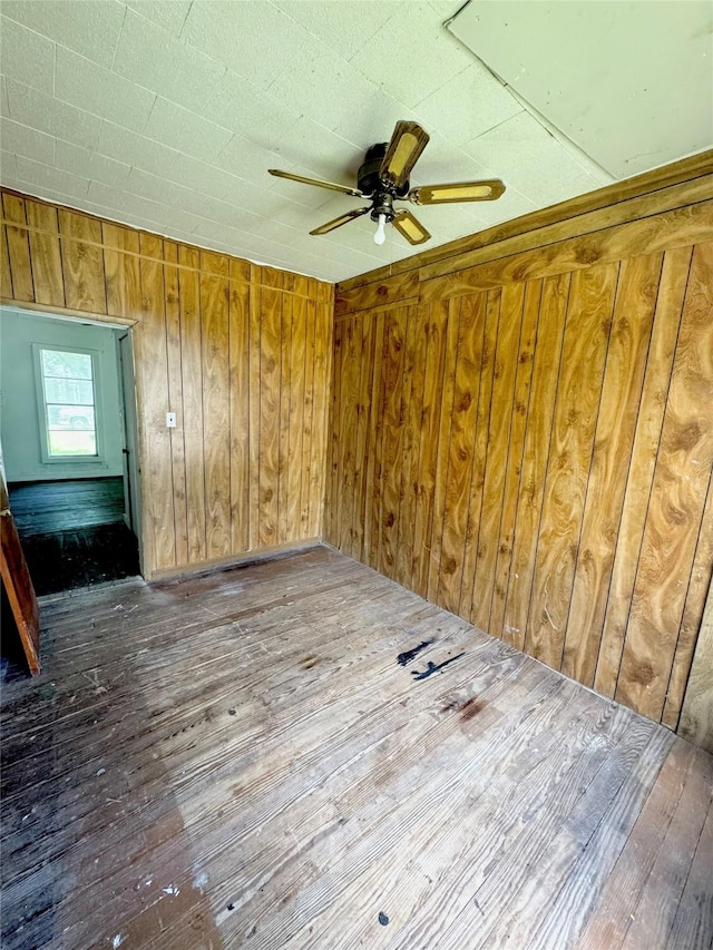 601 Elm St, Teague, TX 75860 - empty room featuring wood-type flooring, ceiling fan, and wood walls