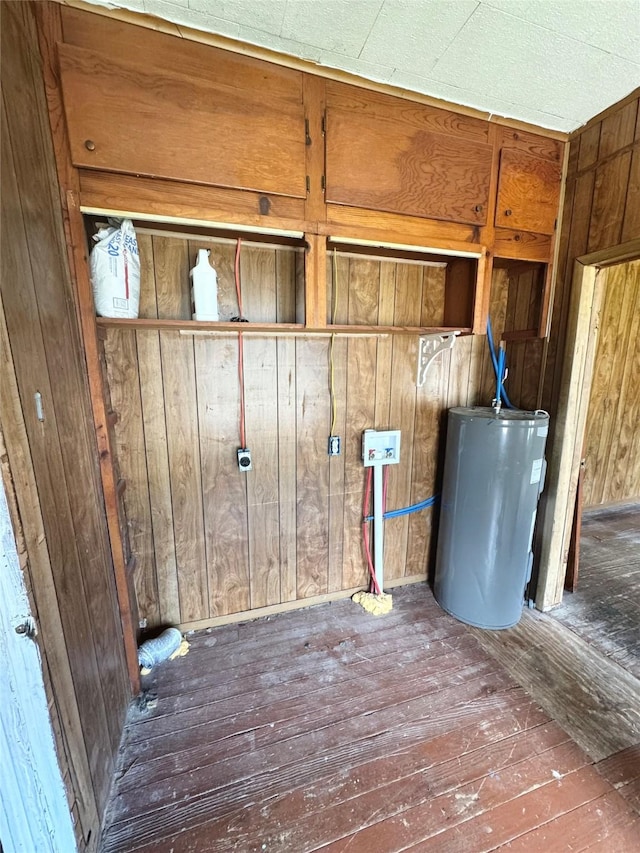 601 Elm St, Teague, TX 75860 - laundry view of water heater, wood finished floors, and wood walls