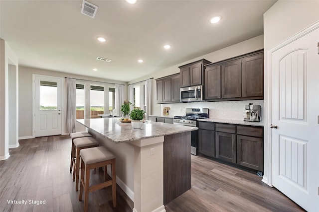 616 Juneau St, Gainesville, TX 76240 - kitchen featuring stainless steel appliances, a center island, dark brown cabinetry, light stone countertops, and tasteful backsplash