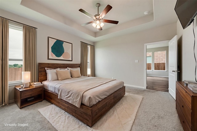 616 Juneau St, Gainesville, TX 76240 - bedroom featuring a tray ceiling, light carpet, multiple windows, and baseboards