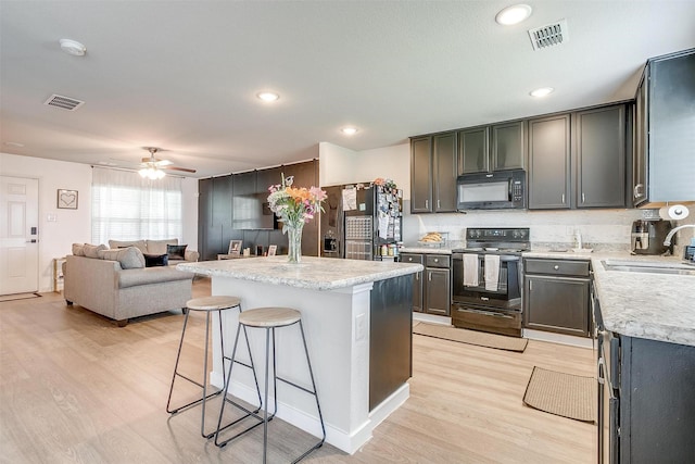 2604 Norite Dr, Fort Worth, TX 76108 - kitchen with black appliances, a sink, light wood finished floors, a kitchen bar, and a ceiling fan