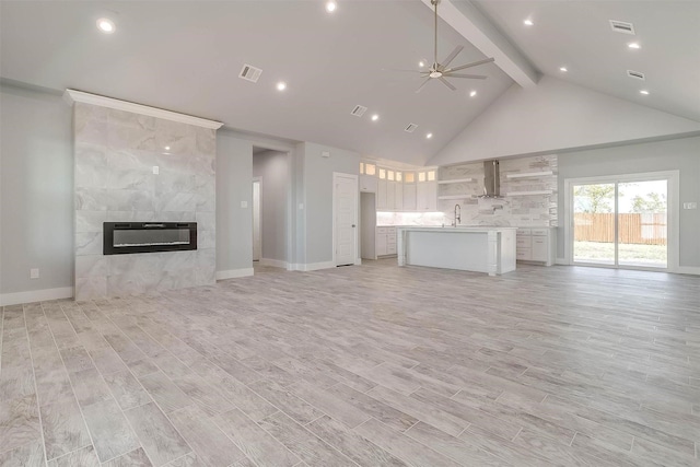 580 Highview Ct, Godley, TX 76044 - unfurnished living room with beamed ceiling, a ceiling fan, a sink, a fireplace, and light wood-style flooring