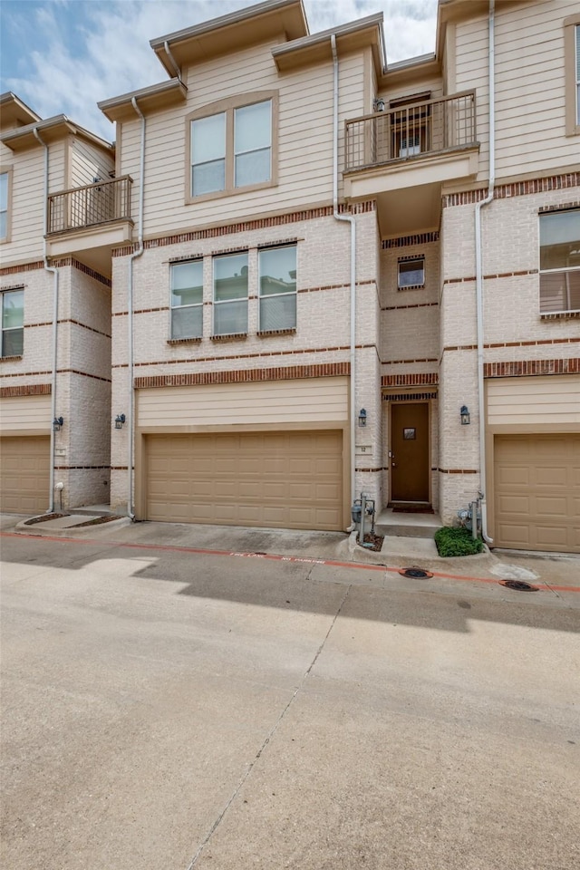 4830 Cedar Springs Rd Unit 12, Dallas, TX 75219 - view of property featuring a balcony, an attached garage, brick siding, and driveway