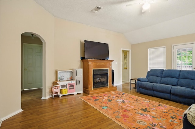 111 Christopher Dr, Cooper, TX 75432 - living area with lofted ceiling, arched walkways, a ceiling fan, wood finished floors, and a fireplace with raised hearth