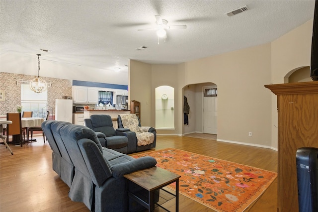 111 Christopher Dr, Cooper, TX 75432 - living room with a ceiling fan, arched walkways, a textured ceiling, light wood finished floors, and a chandelier