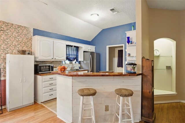 111 Christopher Dr, Cooper, TX 75432 - kitchen with appliances with stainless steel finishes, white cabinetry, light wood finished floors, a peninsula, and vaulted ceiling
