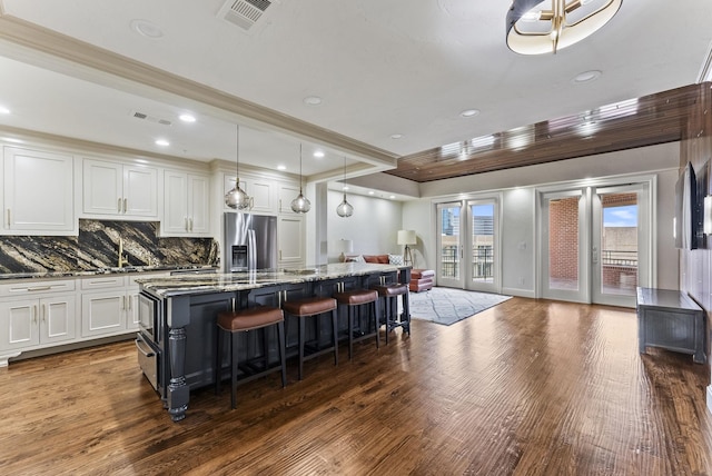 5055 Addison Cir Unit 723, Addison, TX 75001 - kitchen with stainless steel fridge, open floor plan, dark wood-style floors, dark stone counters, and a center island with sink