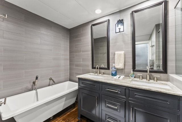 5055 Addison Cir Unit 723, Addison, TX 75001 - bathroom featuring tile walls, a freestanding bath, double vanity, and wood finished floors