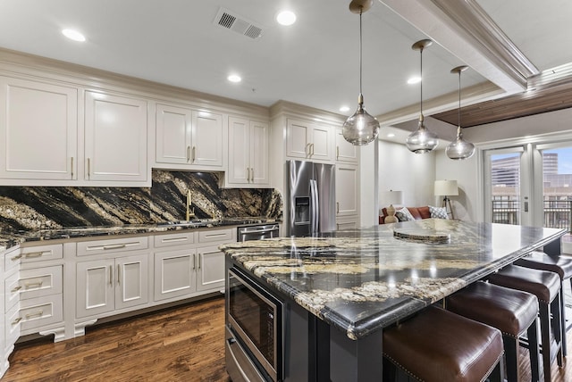5055 Addison Cir Unit 723, Addison, TX 75001 - kitchen with appliances with stainless steel finishes, dark wood finished floors, decorative backsplash, dark stone countertops, and a kitchen bar