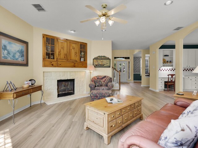 2832 Lincolnshire Dr, Richardson, TX 75082 - living room featuring ceiling fan, light wood-style flooring, a fireplace, baseboards, and arched walkways