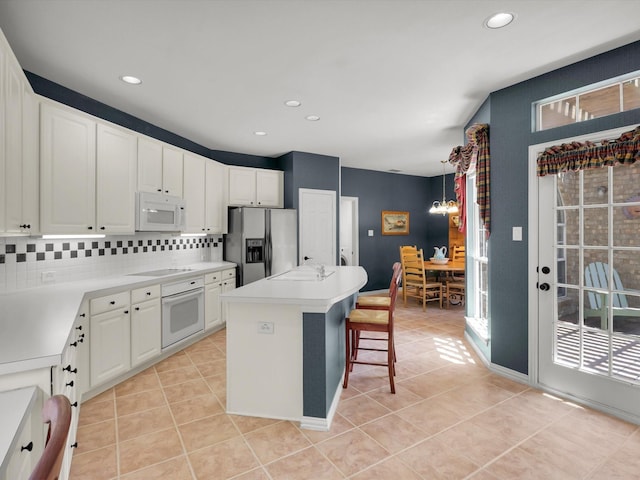 2832 Lincolnshire Dr, Richardson, TX 75082 - kitchen featuring white appliances, a center island, light tile patterned floors, white cabinets, and light countertops