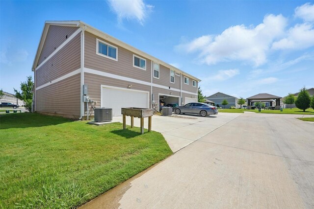 2409 Davenport Dr, Denton, TX 76207 - back of house with central air condition unit, a garage, driveway, and a yard