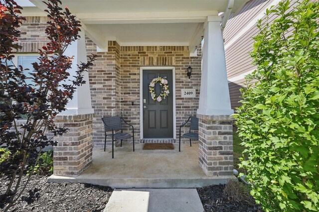 2409 Davenport Dr, Denton, TX 76207 - view of exterior entry with a porch and brick siding