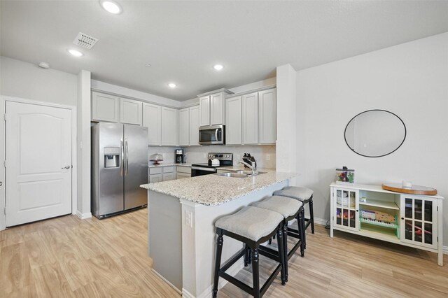 2409 Davenport Dr, Denton, TX 76207 - kitchen with stainless steel appliances, a peninsula, light wood finished floors, light stone countertops, and recessed lighting