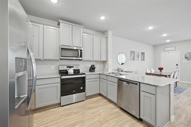 2409 Davenport Dr, Denton, TX 76207 - kitchen featuring appliances with stainless steel finishes, a sink, a peninsula, gray cabinets, and light wood-style flooring