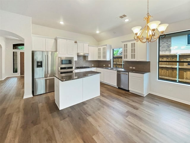 2140 Heather Glen Dr, Rockwall, TX 75087 - kitchen featuring stainless steel appliances, arched walkways, a chandelier, backsplash, and dark countertops