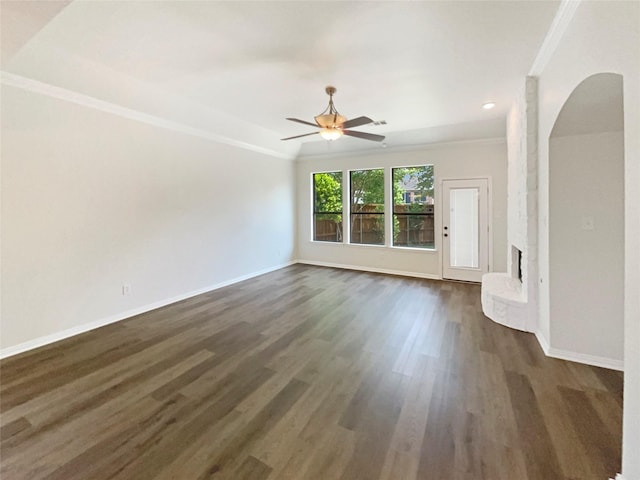 2140 Heather Glen Dr, Rockwall, TX 75087 - unfurnished living room with crown molding, arched walkways, dark wood-style flooring, baseboards, and a brick fireplace