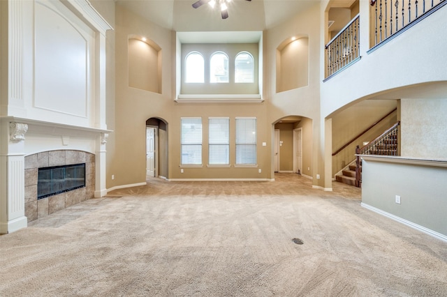 3500 Corkwood Dr, Frisco, TX 75033 - unfurnished living room with a towering ceiling, a ceiling fan, a fireplace, carpet flooring, and stairs