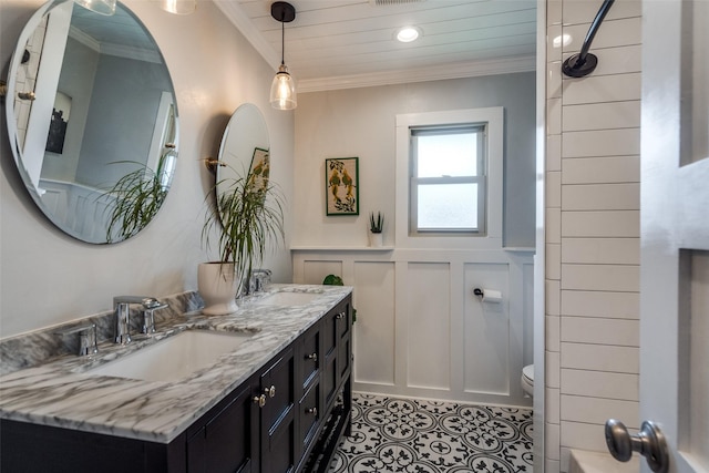 9923 Harwell Dr, Dallas, TX 75220 - bathroom featuring a decorative wall, crown molding, double vanity, toilet, and a wainscoted wall