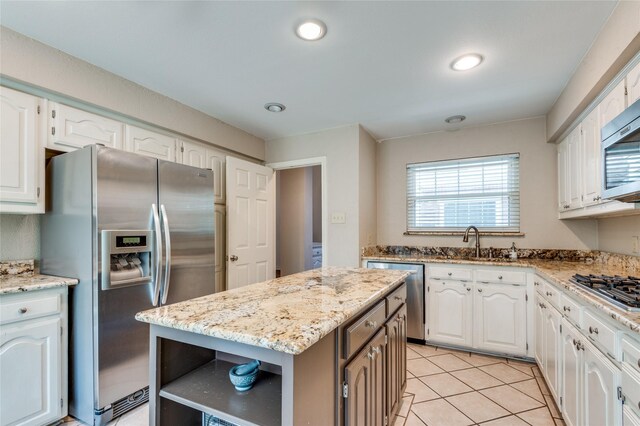 924 Mccoy Dr, Irving, TX 75062 - kitchen featuring appliances with stainless steel finishes, white cabinetry, light stone counters, light tile patterned floors, and a sink