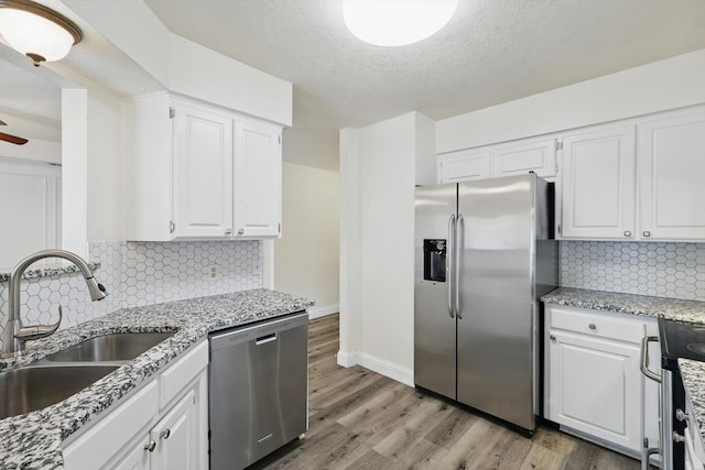 7616 Teresa Ct, North Richland Hills, TX 76182 - kitchen with appliances with stainless steel finishes, a sink, light wood finished floors, white cabinetry, and baseboards