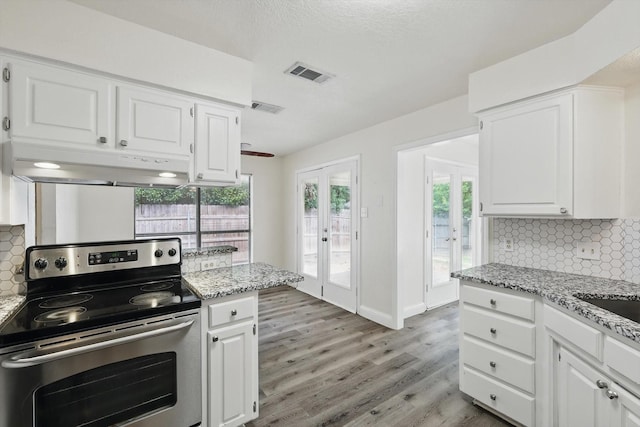 7616 Teresa Ct, North Richland Hills, TX 76182 - kitchen with stainless steel electric range, under cabinet range hood, french doors, light wood-style floors, and tasteful backsplash