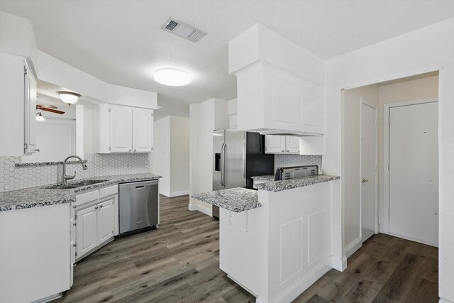 7616 Teresa Ct, North Richland Hills, TX 76182 - kitchen with stainless steel dishwasher, a sink, tasteful backsplash, a peninsula, and wood finished floors