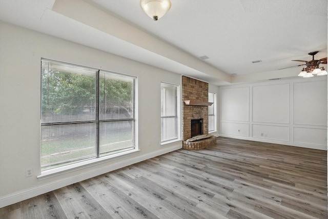 7616 Teresa Ct, North Richland Hills, TX 76182 - unfurnished living room featuring ceiling fan, wood finished floors, a decorative wall, a brick fireplace, and baseboards