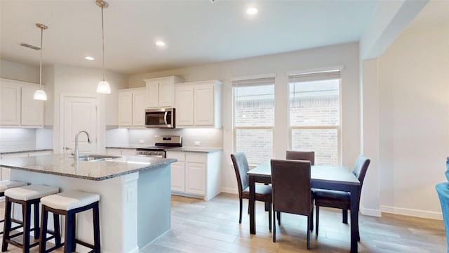 15941 Bronte Ln, Fort Worth, TX 76247 - kitchen featuring stainless steel appliances, a sink, an island with sink, a kitchen bar, and decorative backsplash