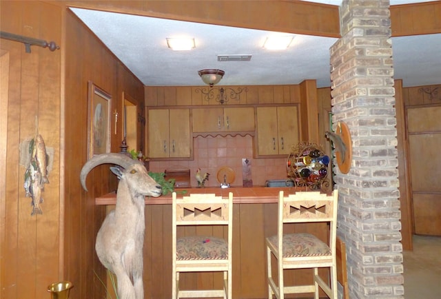 135 Lakeview, Brady, TX 76825 - kitchen featuring ornate columns, wood walls, and tasteful backsplash