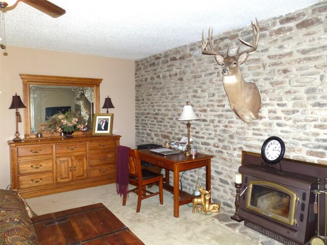 135 Lakeview, Brady, TX 76825 - living area featuring a wood stove, light carpet, a textured ceiling, and a ceiling fan