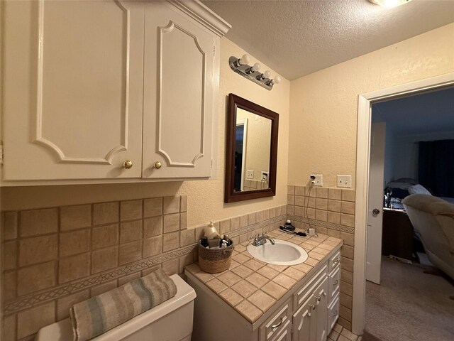 4 Preston Pl, Mineral Wells, TX 76067 - bathroom featuring tile walls, a textured ceiling, a textured wall, toilet, and vanity