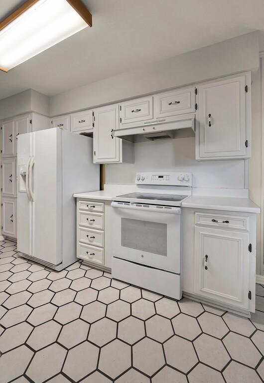 2832 Wooded Acres Dr, Waco, TX 76710 - kitchen with white appliances, under cabinet range hood, white cabinets, and light countertops