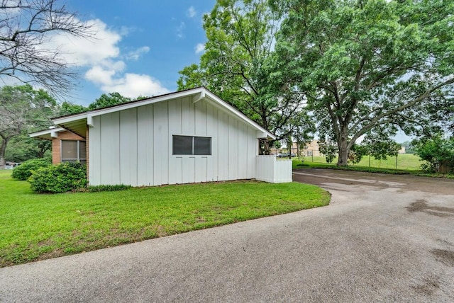 2832 Wooded Acres Dr, Waco, TX 76710 - view of side of home with board and batten siding, a lawn, and asphalt driveway