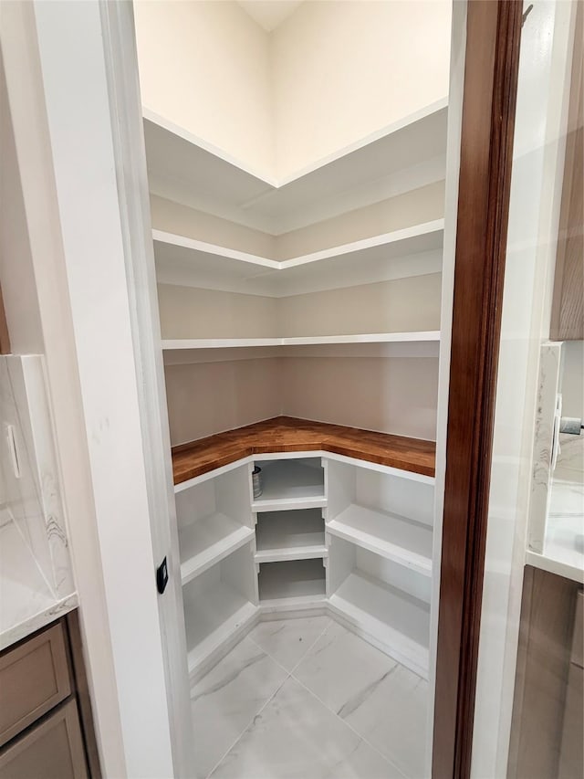 2815 Pall Mall Ave, Dallas, TX 75241 - kitchen with stainless steel appliances, a sink, light marble finish floors, a kitchen island, and brown cabinetry