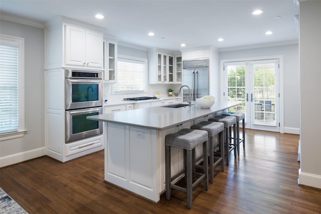 4684 Belclaire Ave, Highland Park, TX 75209 - kitchen with a sink, appliances with stainless steel finishes, ornamental molding, an island with sink, and white cabinetry