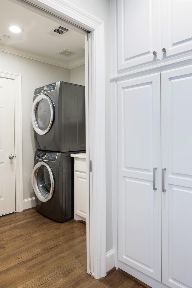 4684 Belclaire Ave, Highland Park, TX 75209 - washroom with stacked washer and clothes dryer, crown molding, dark wood finished floors, baseboards, and cabinet space