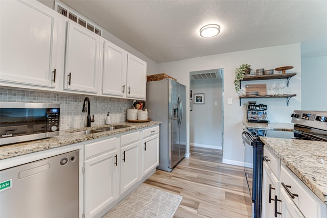 6117 Magnolia Ln, Rowlett, TX 75089 - kitchen featuring stainless steel appliances, a sink, open shelves, white cabinets, and baseboards