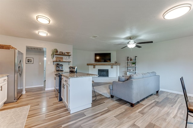 6117 Magnolia Ln, Rowlett, TX 75089 - living area featuring light wood-type flooring, ceiling fan, a brick fireplace, and baseboards