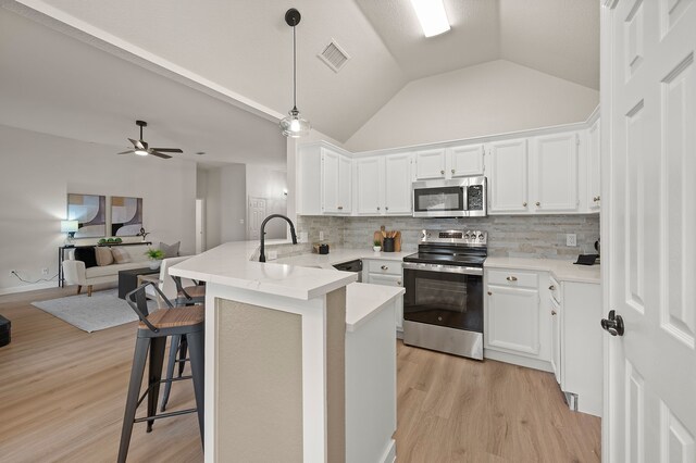 28 Alamosa Dr, Trophy Club, TX 76262 - kitchen featuring stainless steel appliances, a peninsula, open floor plan, lofted ceiling, and white cabinetry