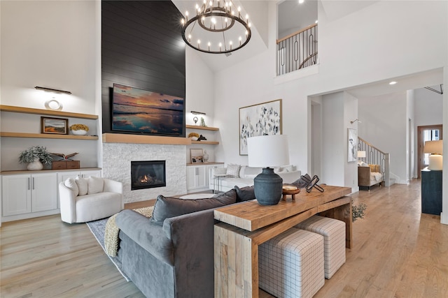1525 Langford Ln, Celina, TX 75009 - living room featuring high vaulted ceiling, light wood-style floors, stairs, a chandelier, and a stone fireplace