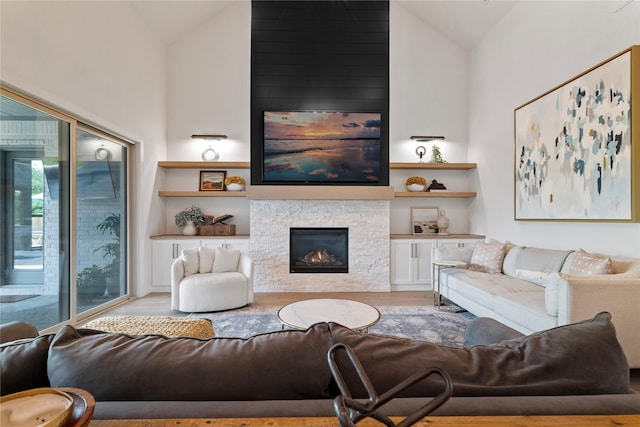 1525 Langford Ln, Celina, TX 75009 - living area featuring light wood-type flooring, a glass covered fireplace, healthy amount of natural light, and high vaulted ceiling