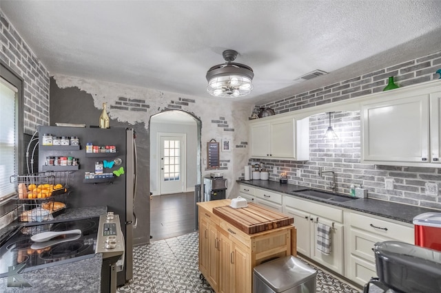 202 E Ross St, Rising Star, TX 76471 - kitchen with arched walkways, a sink, wooden counters, freestanding refrigerator, and white cabinetry