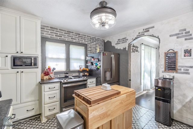 202 E Ross St, Rising Star, TX 76471 - kitchen featuring stainless steel appliances, white cabinetry, arched walkways, a center island, and light tile patterned floors